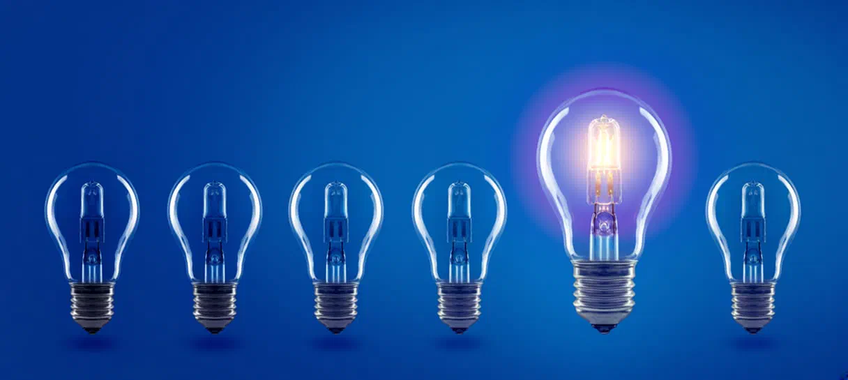 Six light bulbs in a row against a blue background. The fifth bulb is larger and lit.